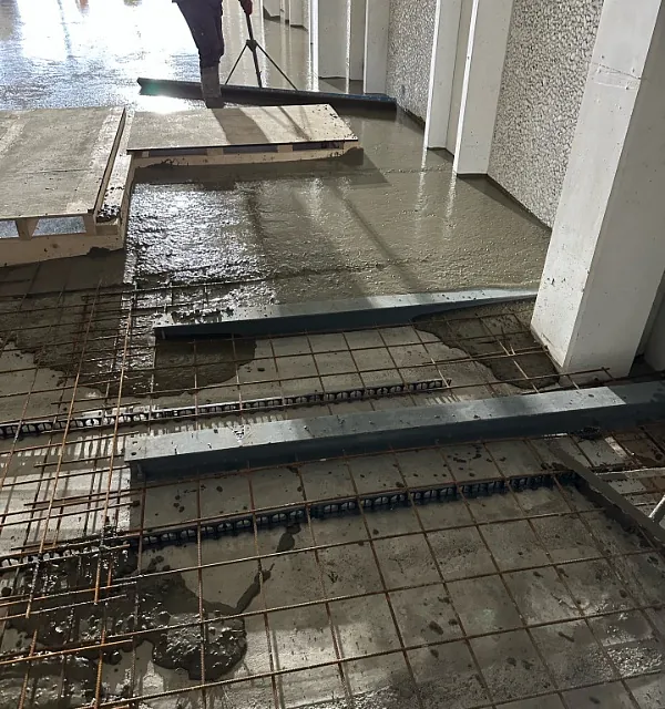 Arbeider fordeler fersk betong over armering med avrettingsverktøy